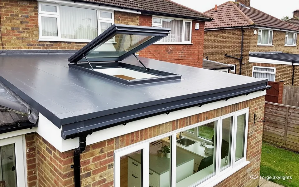 An opening rooflight propped open on an extension roof, a brick house behind