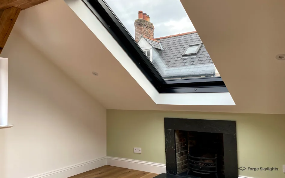 A large roof window above a fireplace in a loft room