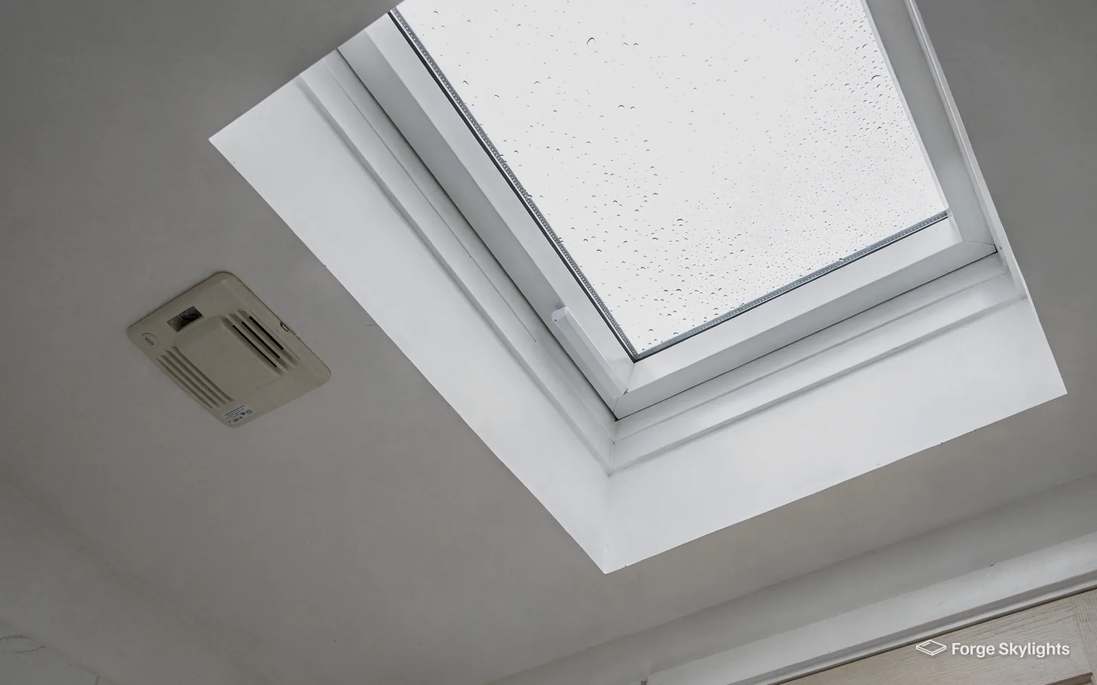 Water droplets on the inside of rooflight glass beside an extractor vent