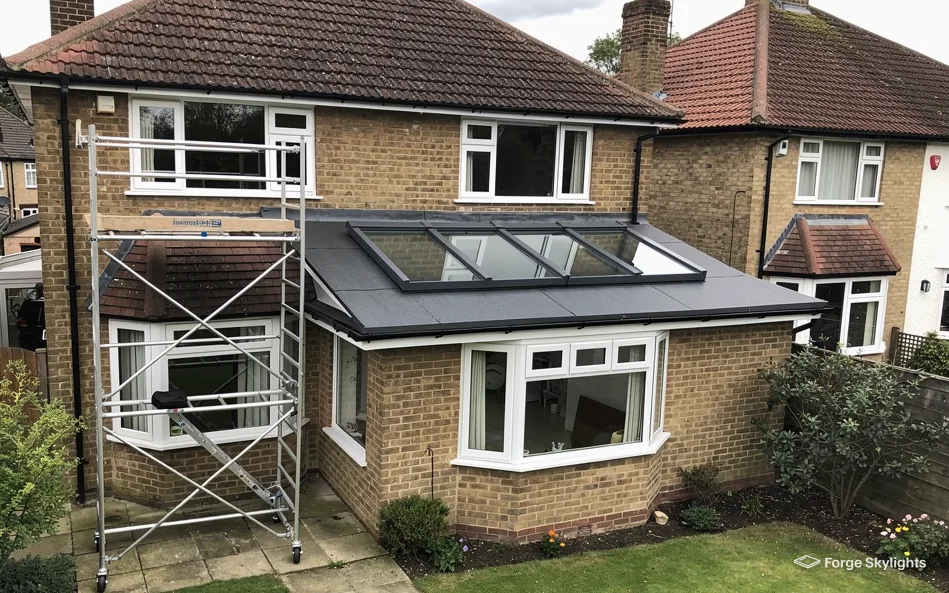 A brick house with a roof lantern on its rear extension and a scaffold tower beside it