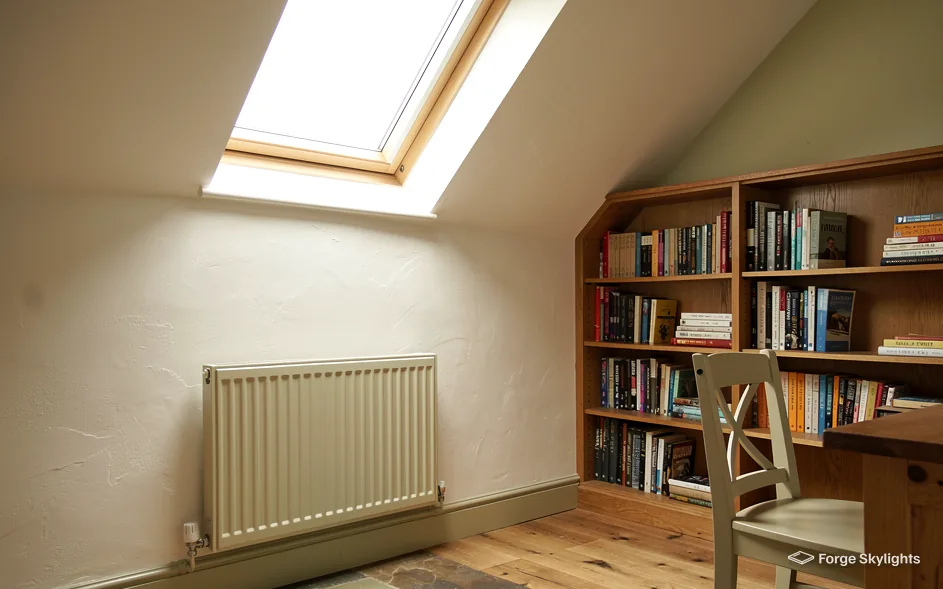 A loft study with a bookcase and radiator under a roof window