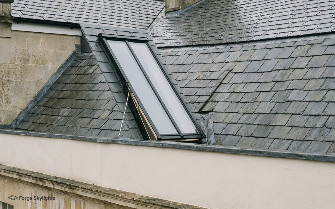 A tall narrow conservation rooflight standing open in a slate roof