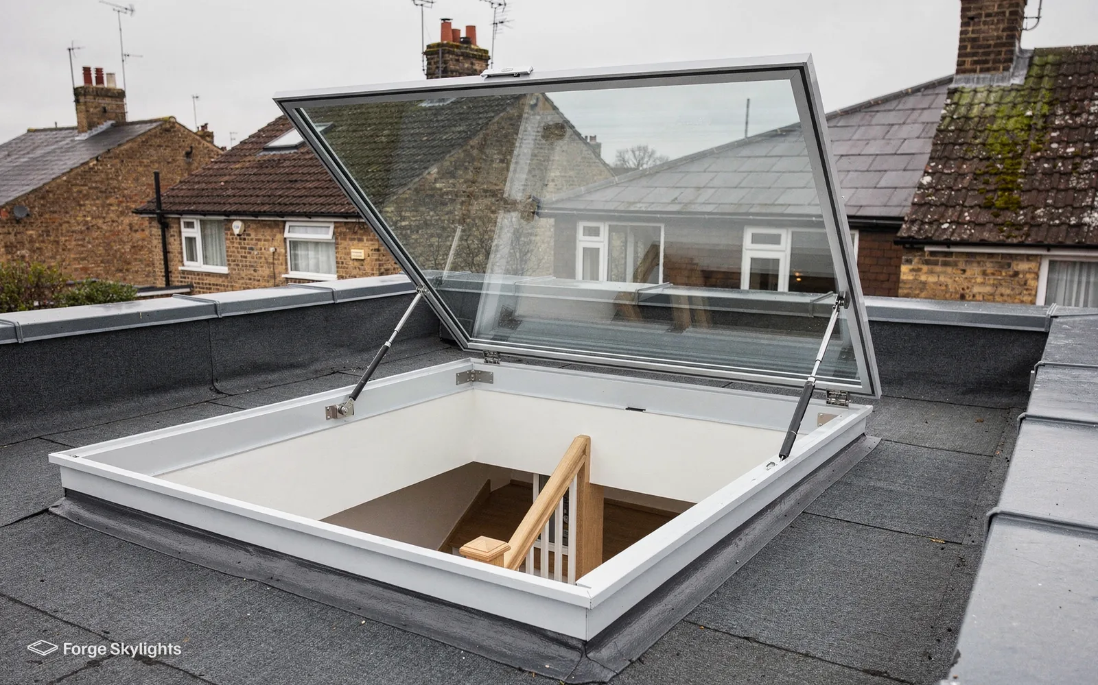 A hinged roof access rooflight open on a flat roof, with a stair visible below it