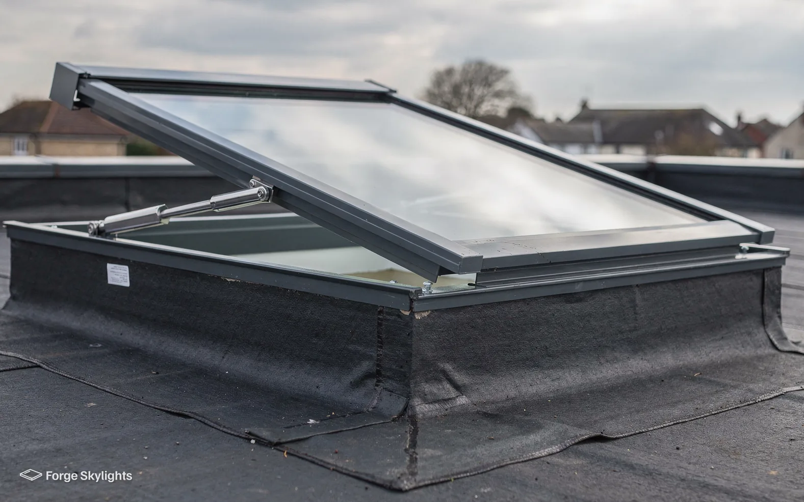 An opening rooflight on its kerb, partly open on a flat roof
