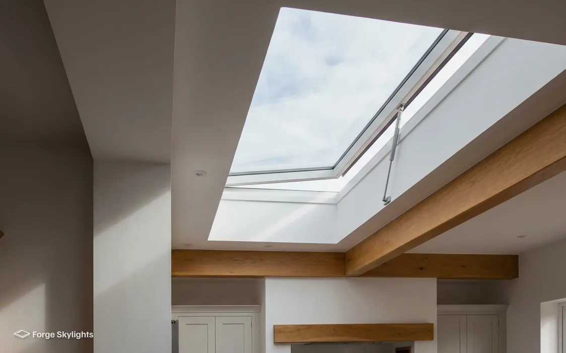 An opening rooflight seen from inside a room with timber beams