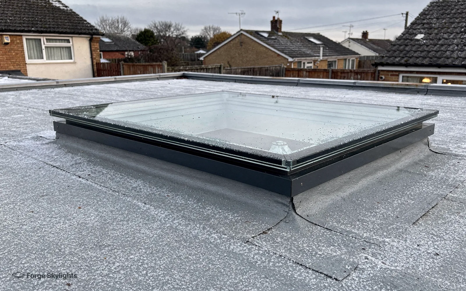 A flat rooflight on an upstand on a flat roof, houses behind