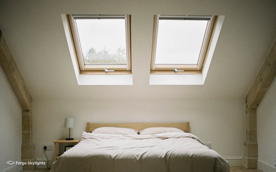 A loft bedroom with two pine roof windows above the bed