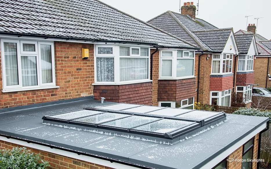 A long flat rooflight on an extension roof with semi detached houses behind