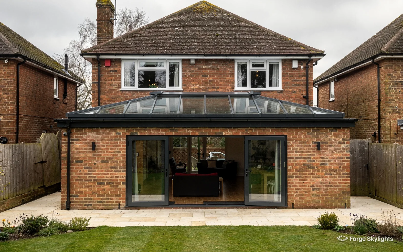 The rear of a red brick detached house with a roof lantern on its extension