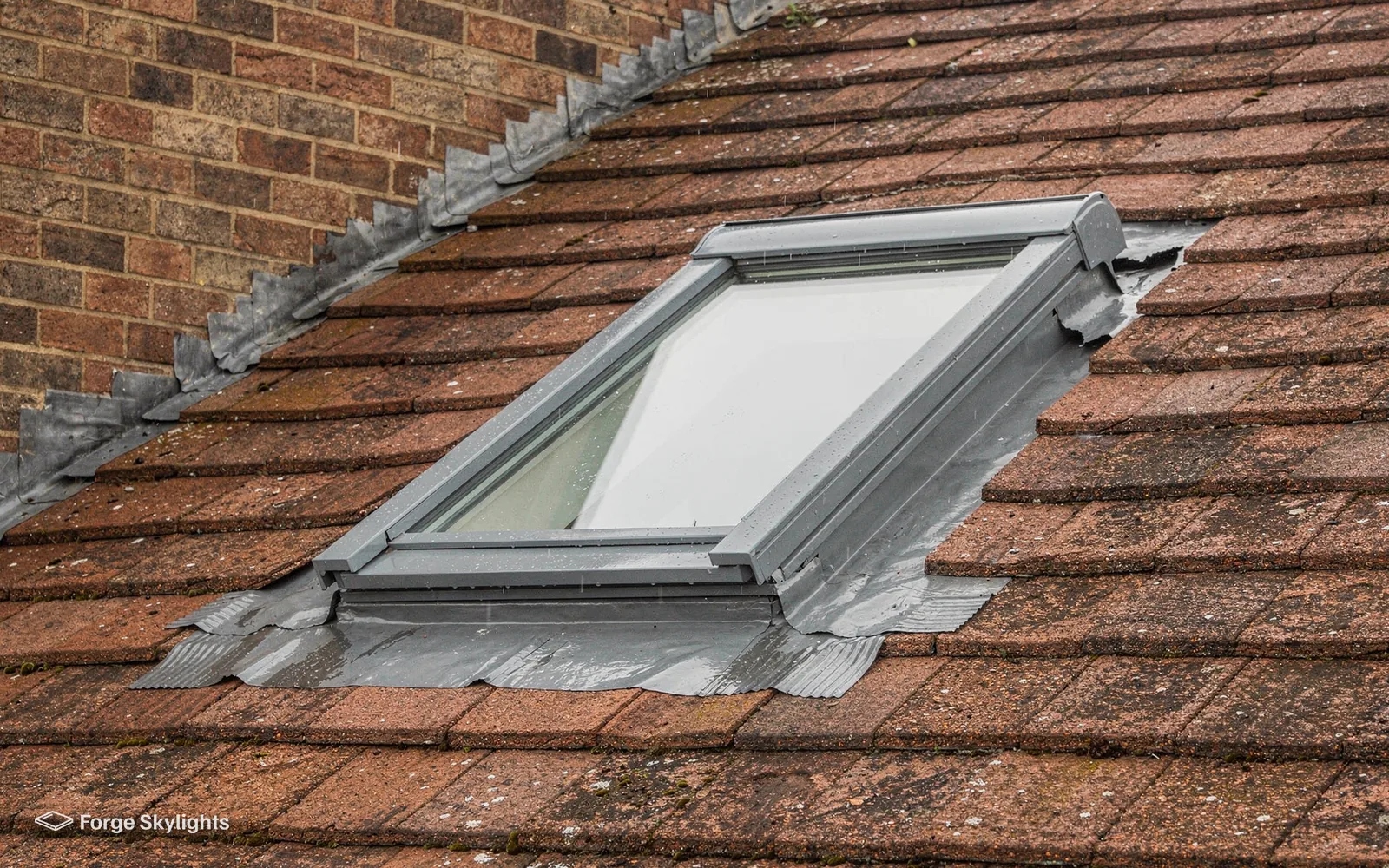 Close view of clay roof tiles with a roof window and its flashing worked in between them