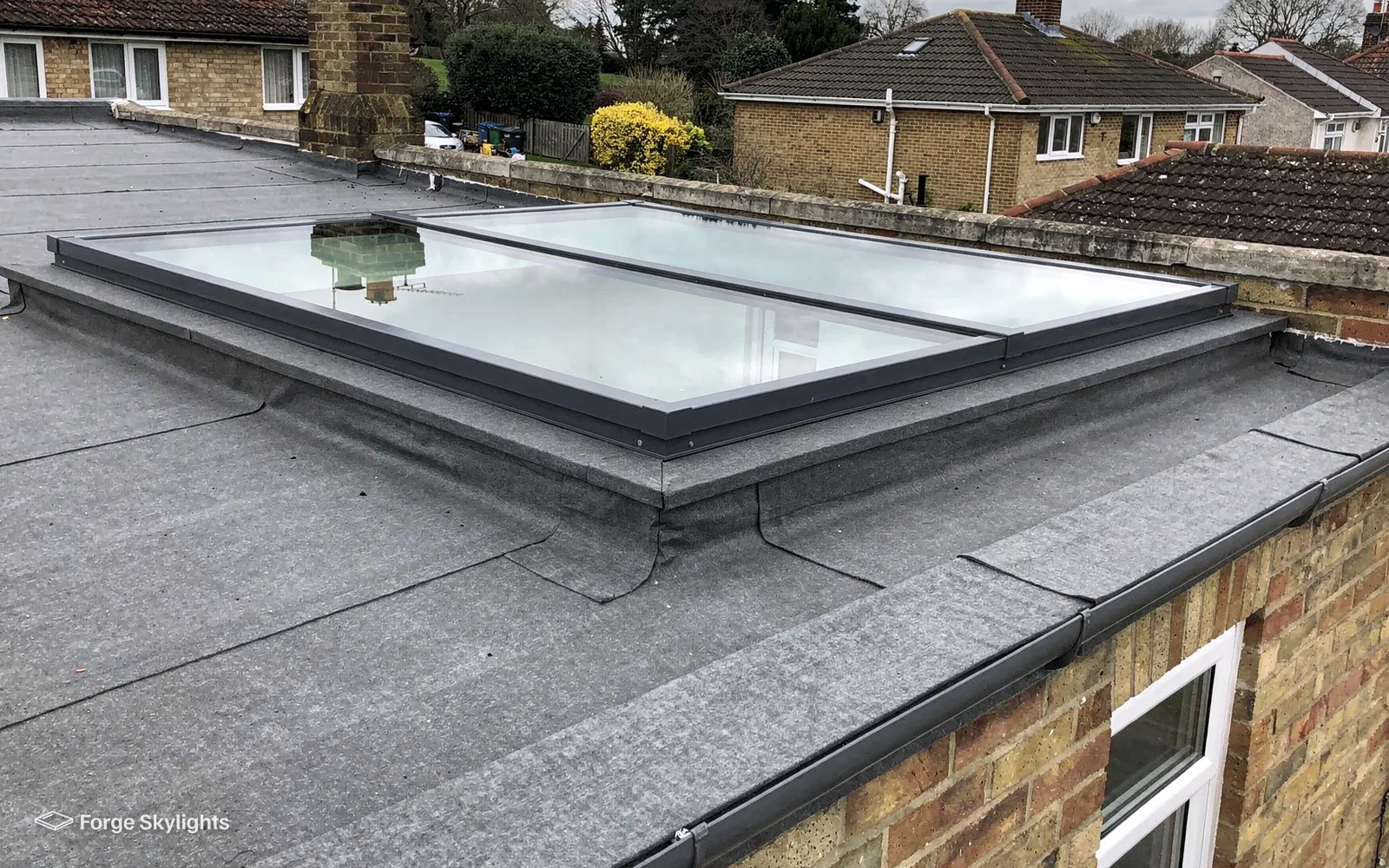 A double flat rooflight on an extension roof with red brick houses behind