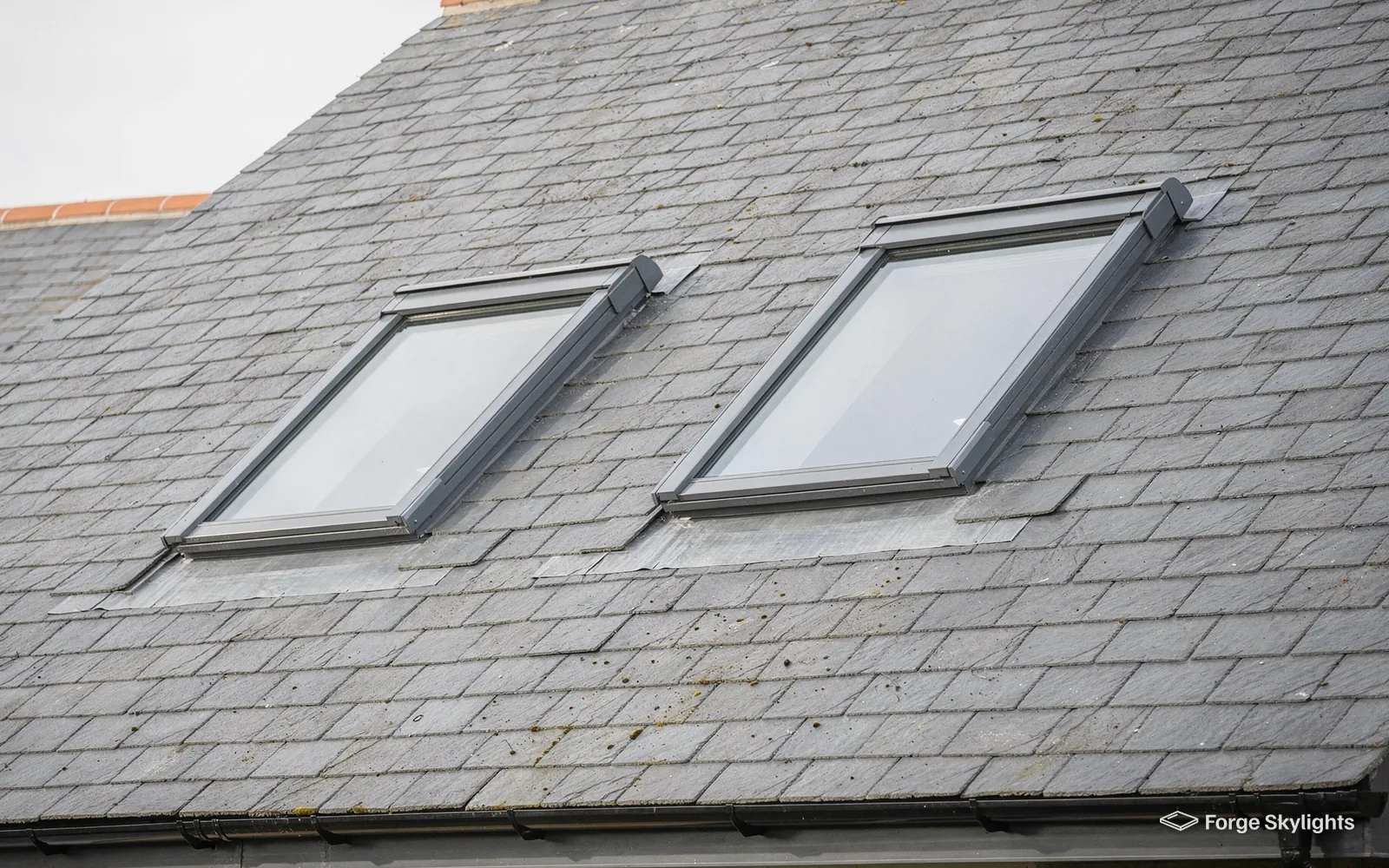 Two roof windows side by side in a slate roof