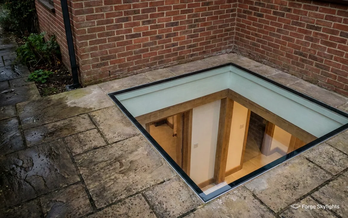 A walk-on glass panel in wet paving looking down into a room