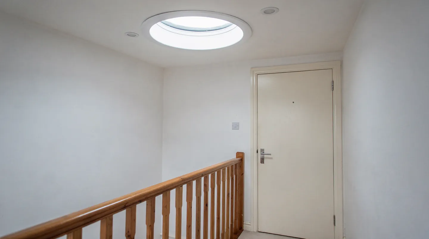 A round sun tunnel diffuser in the ceiling of an upstairs landing